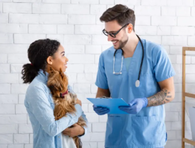 Veterinarian Talking to Client Holding Her Dog